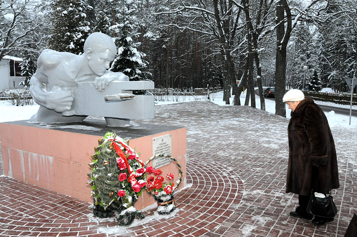 A l’entrée du parc national de Bialowieza, une dame vient déposer une gerbe au pied du monument dédié aux résistants biélorusses contre l’envahisseur allemand.