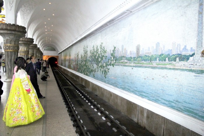 Coréenne en costume traditionnel dans le métro de Pyongyang, mêlant marbres et lustres aux mosaïques et fresques consacrées à la présentation de l’idéologie officielle, le Juche.